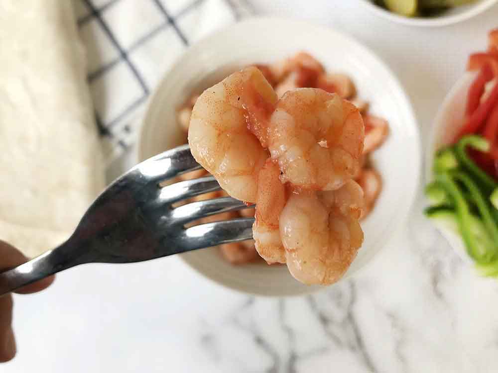 A forkful of spicy shrimp with tomato sauce.