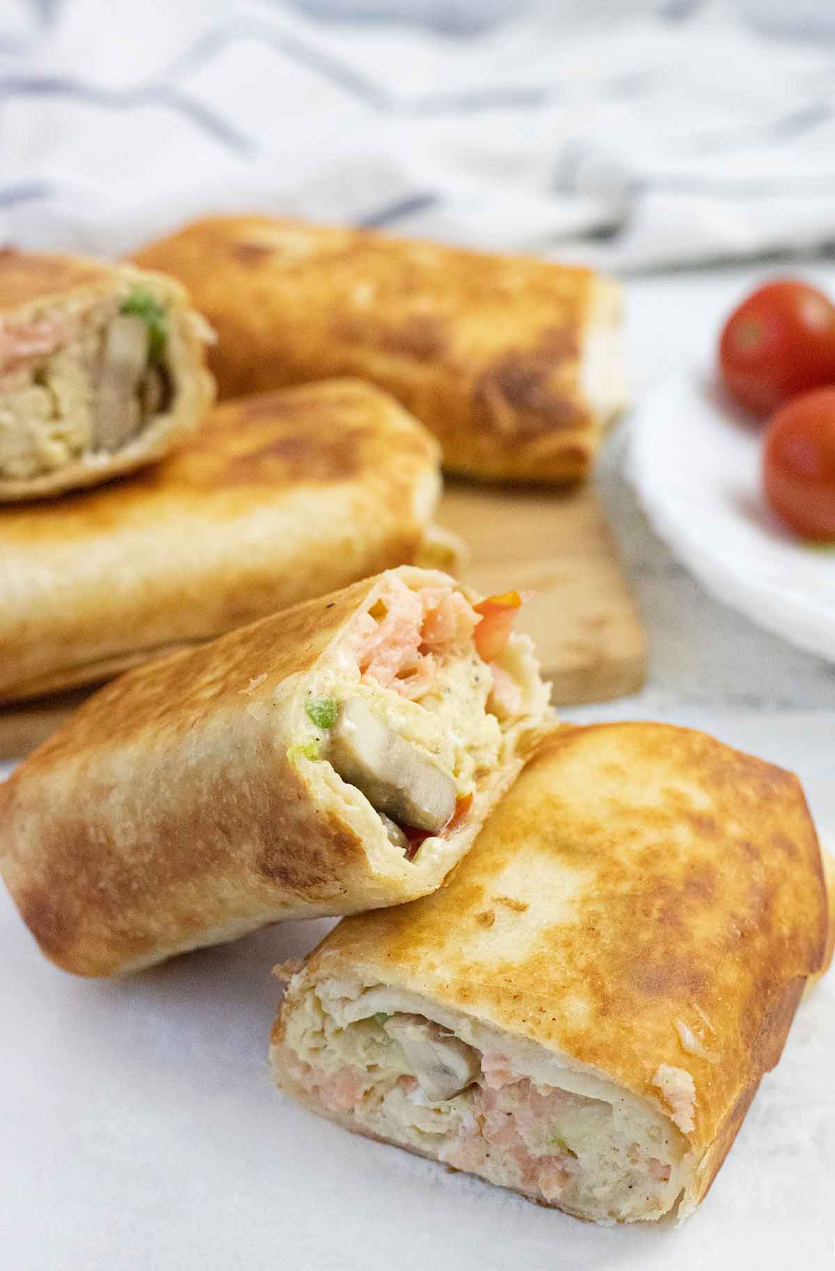 One pan toasted breakfast burritos cut and filled with salmon, mushrooms, cheese and eggs.