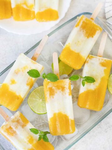 Tropical popsicles in a pan full of ice cubs and lime.