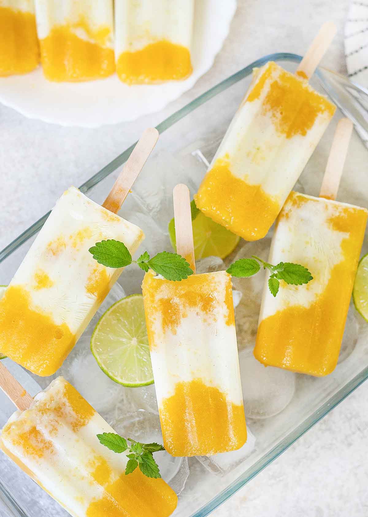 Tropical popsicles in a pan full of ice cubs and lime.