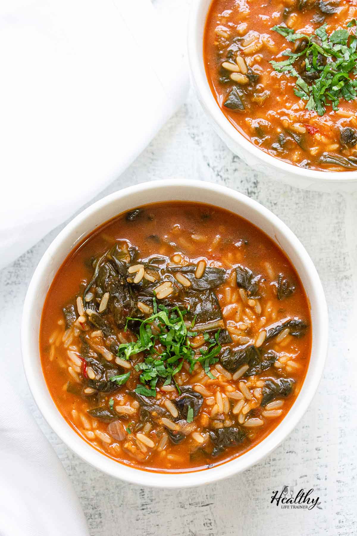 African spinach stew with rice served in 2 bowls.