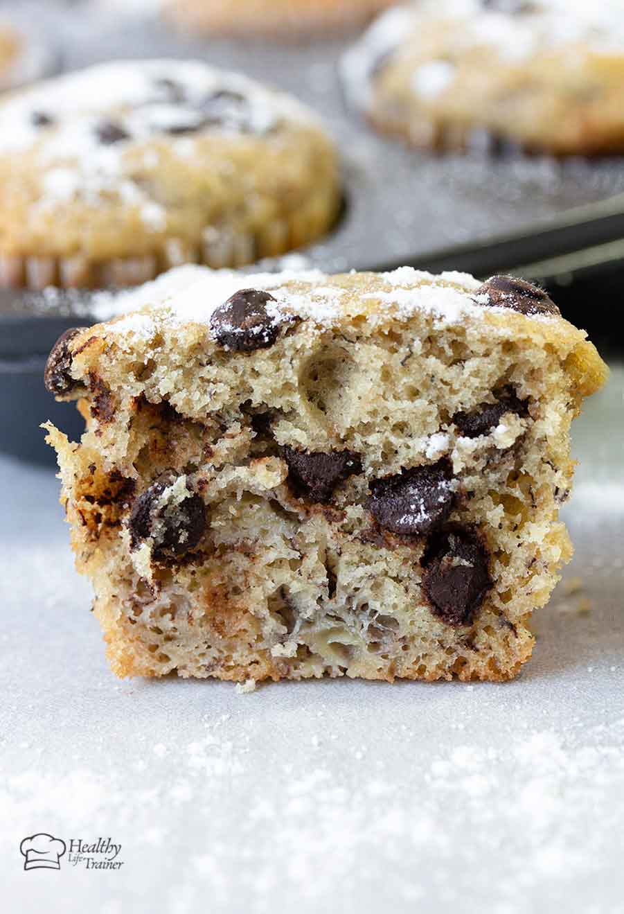 banana muffin cut into half showing the chocolate chips and the banana chunks.