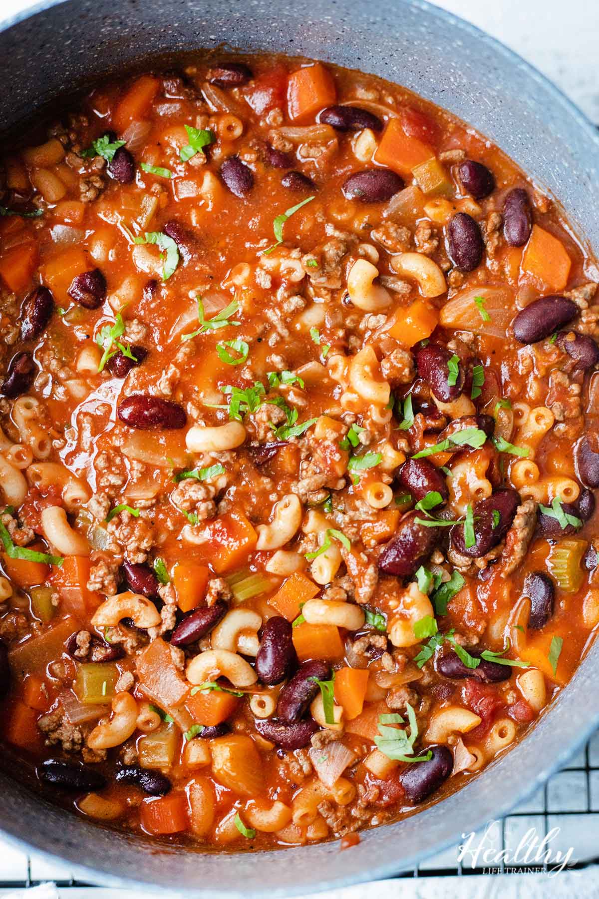 Beef and macaroni soup with veggies and beans in a large pot.