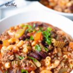 A big bowl of beef and macaroni soup with veggies and beans.