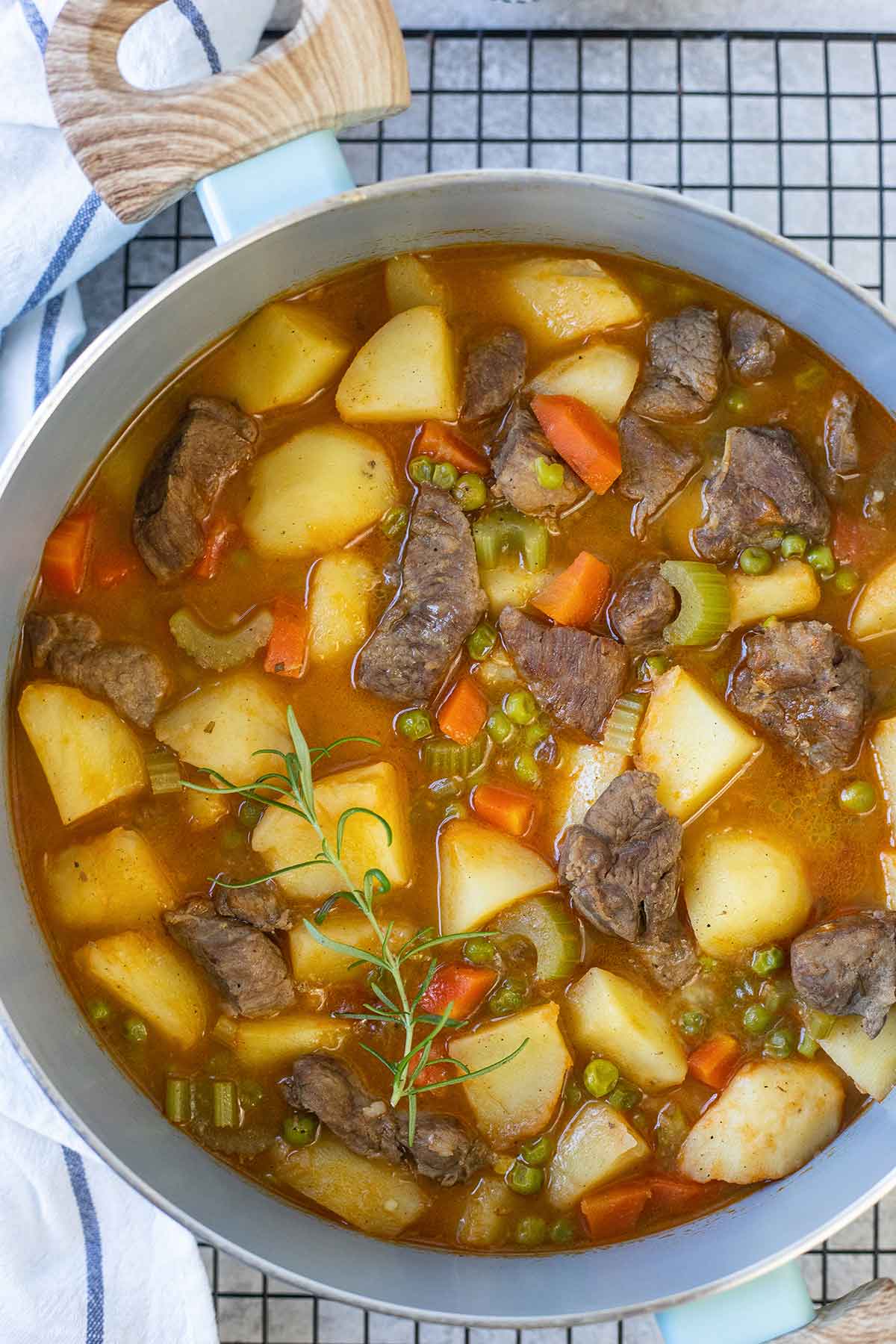 A pot filled with middle eastern lamb stew and a sprig of rosemary on top.