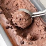 scooping no churn chocolate ice cream from a container.