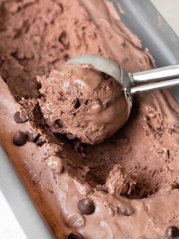 scooping no churn chocolate ice cream from a container.