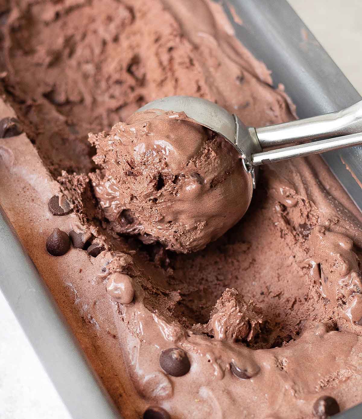 scooping no churn chocolate ice cream from a container.