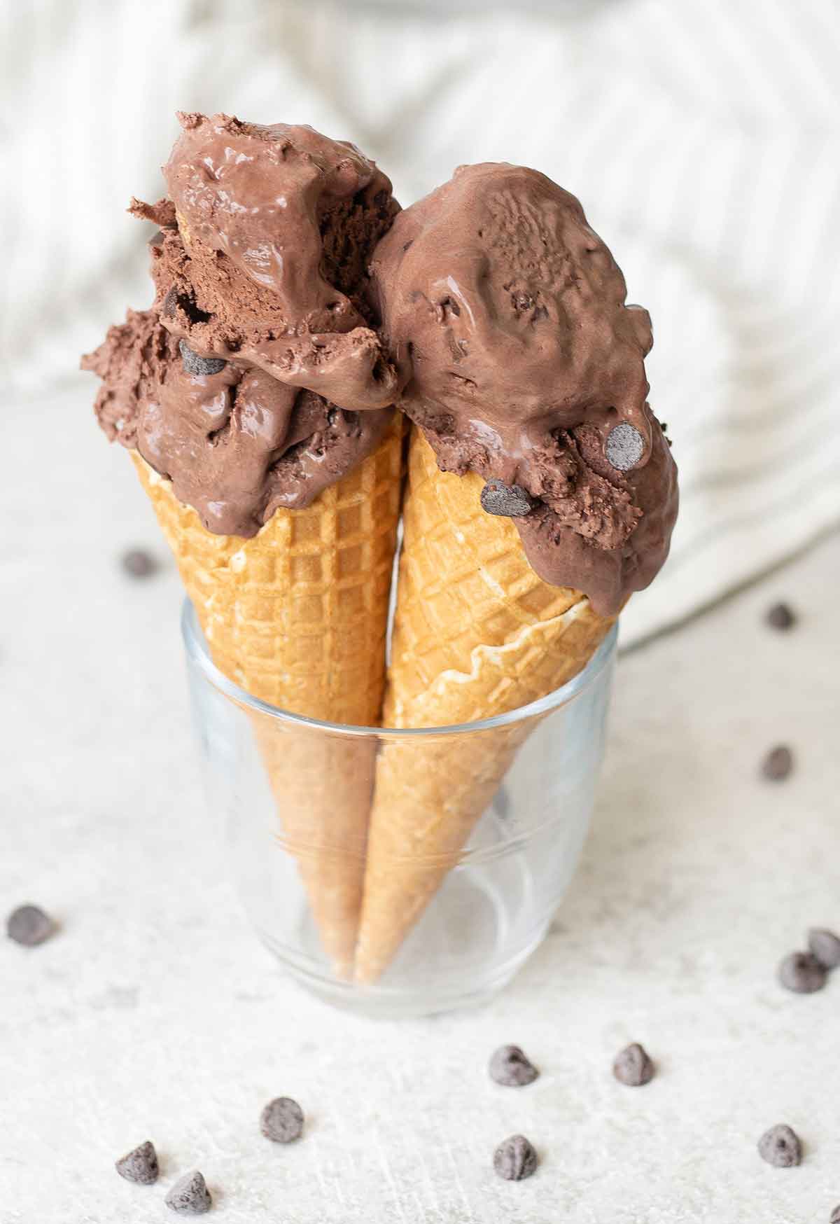 2 cones of no churn chocolate ice cream and some chocolate chips around them.