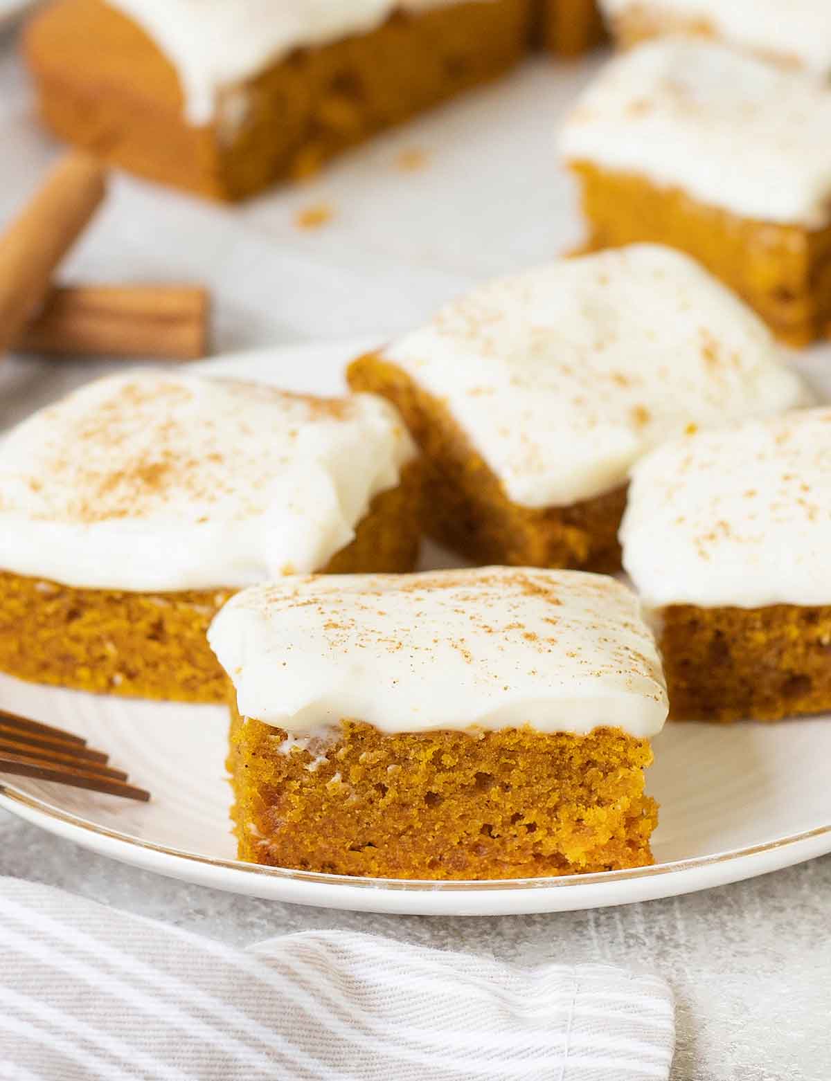 Some of the Pumpkin bars are in a serving plate topped with Cream Cheese Frosting.