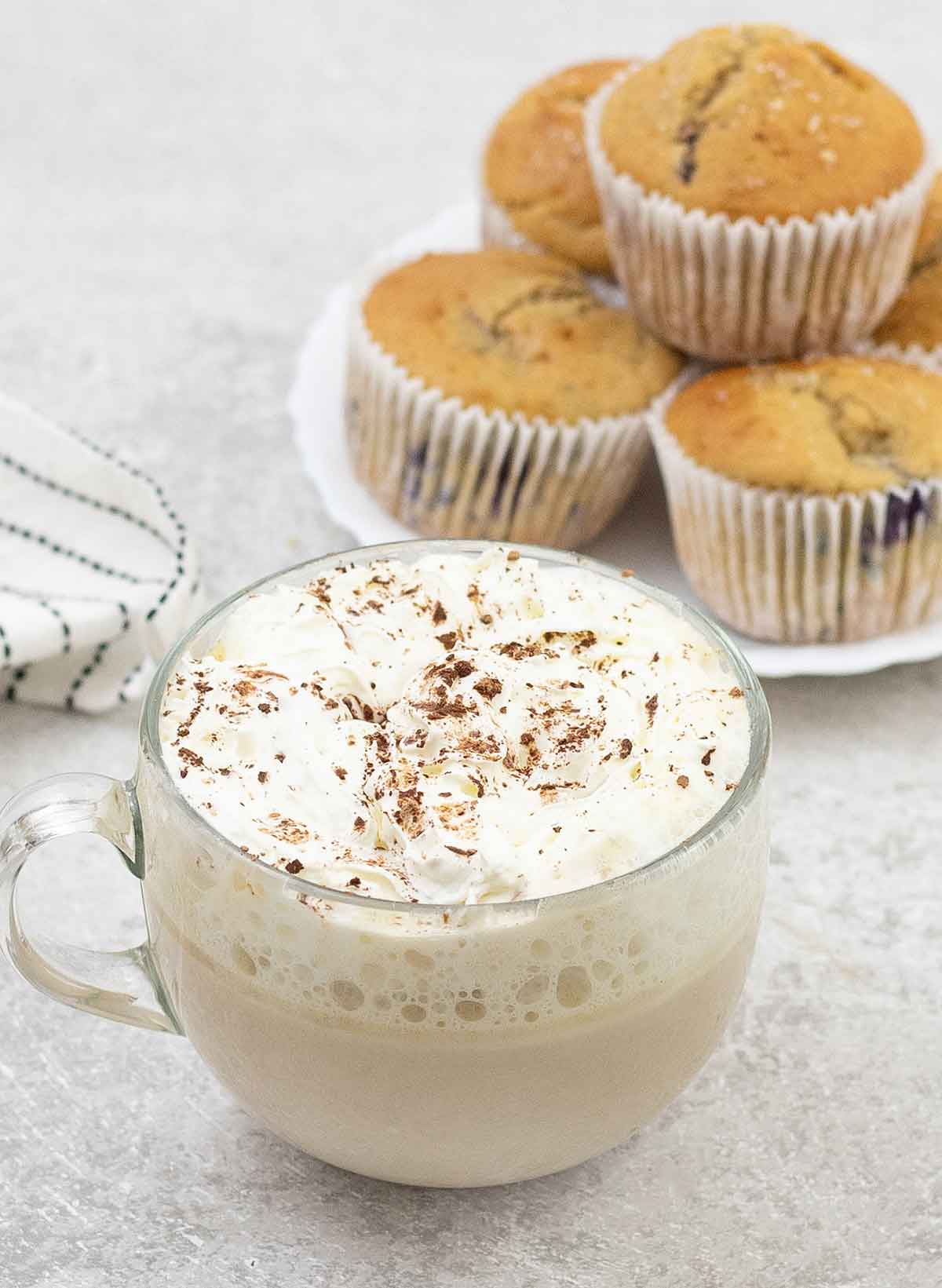 white chocolate latte cup and some muffins in the background.