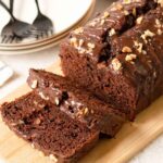 Chocolate banana bread drizzled with melted chocolate and topped with walnuts.