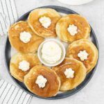 Sweet cream pancakes topped with whipped cream and maple syrup.