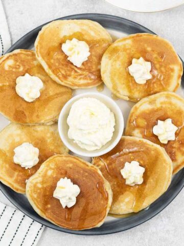 Sweet cream pancakes topped with whipped cream and maple syrup.