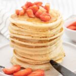 Almond milk pancakes topped with fresh strawberries and drizzled with honey.