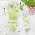 Cucumber Water in a glasses flavored with lemon slices and mint leaves.