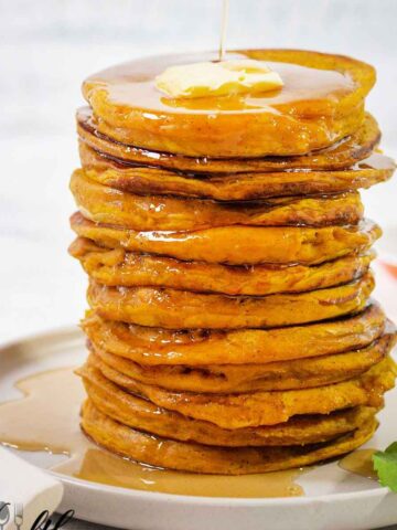 pumpkin pancakes topped with butter and drizzled with maple syrup.