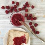 keto Raspberry Jam is in a jar, and fresh Raspberries are around.