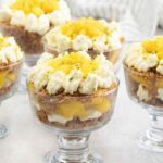 kunafa with mango and cheesecake in cups topped with whipped cream.