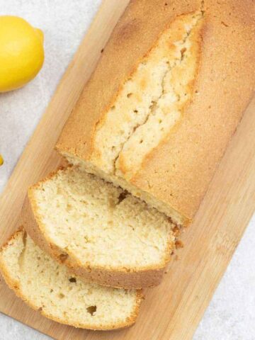 madeira loaf cake on a serving board along with fresh lemons.