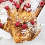 Overnight French Toast in a casserole pan topped with raspberry.