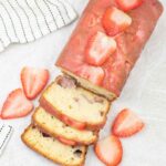 strawberry loaf cake topped with strawberry glaze and fresh slices of strawberries.