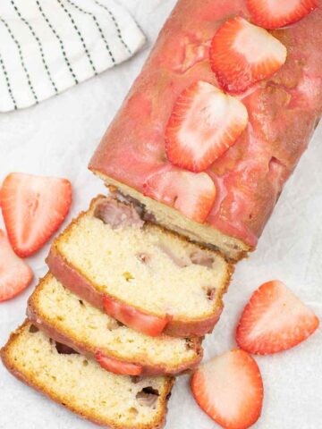 strawberry loaf cake topped with strawberry glaze and fresh slices of strawberries.