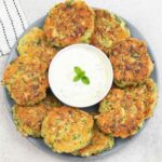 courgette fritters around a small bowl of yogurt dip.