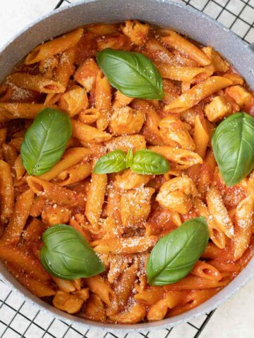 Chicken Arrabbiata Pasta in a pot topped with fresh basil leaves.