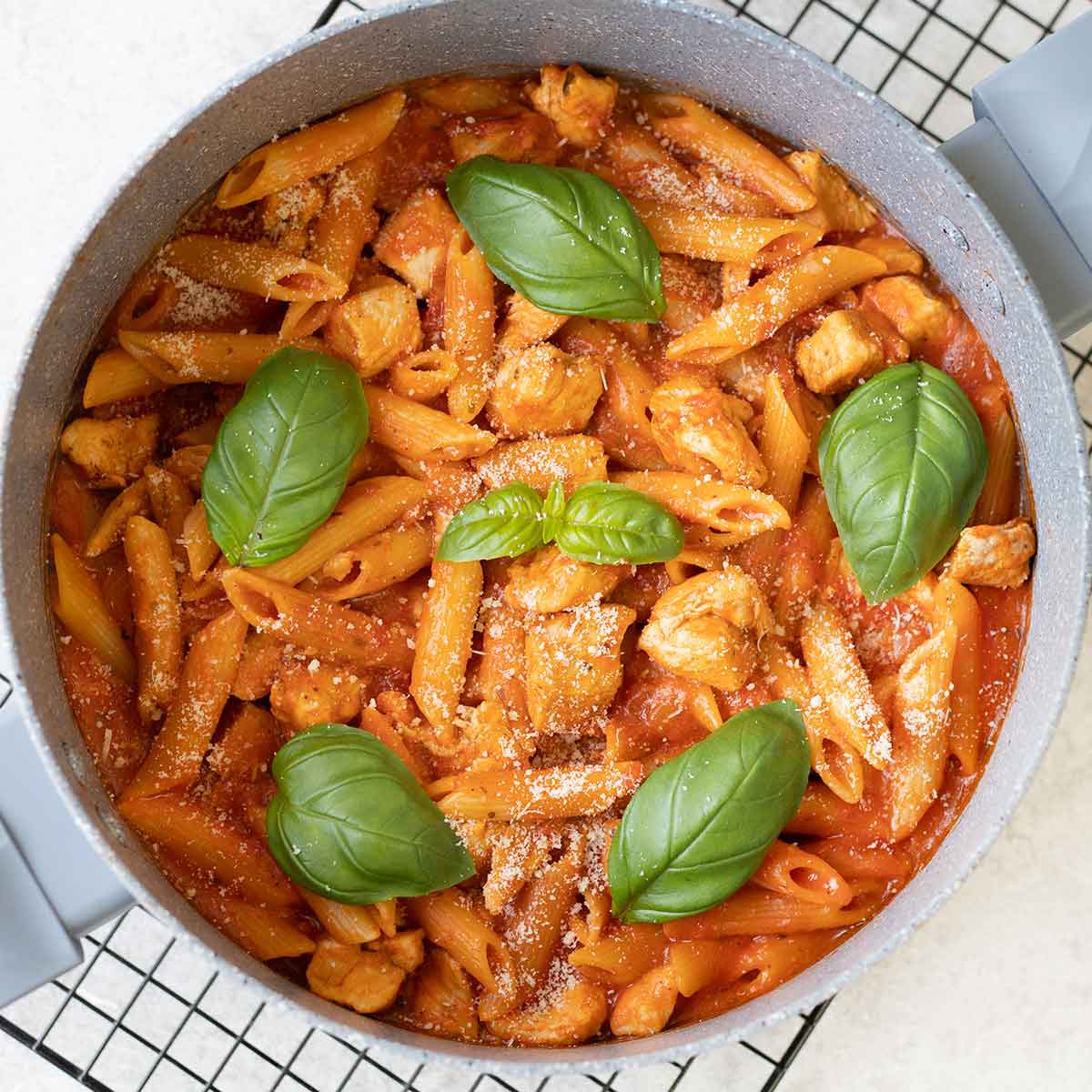 Chicken Arrabbiata Pasta in a pot topped with fresh basil leaves.